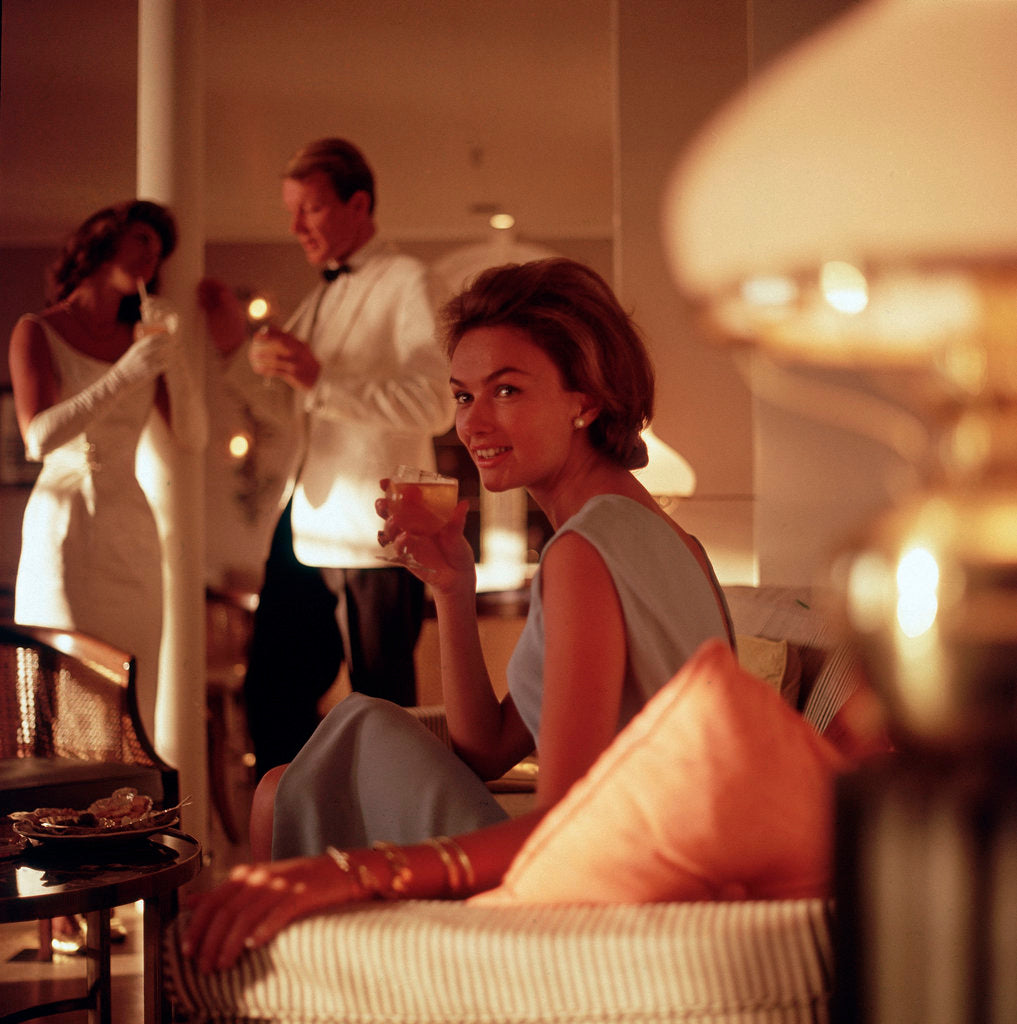 Detail of A smartly attired female passenger enjoys an evening tipple aboard an unspecified cruise ship by Marine Photo Service