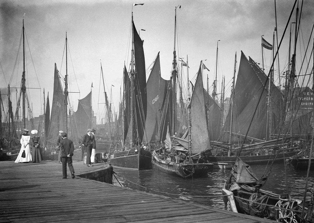 Detail of A view from the wooden quay at Lowestoft, Suffolk, looking across the trawl basin filled with a large number of sailing trawlers by Smiths Suitall Ltd.