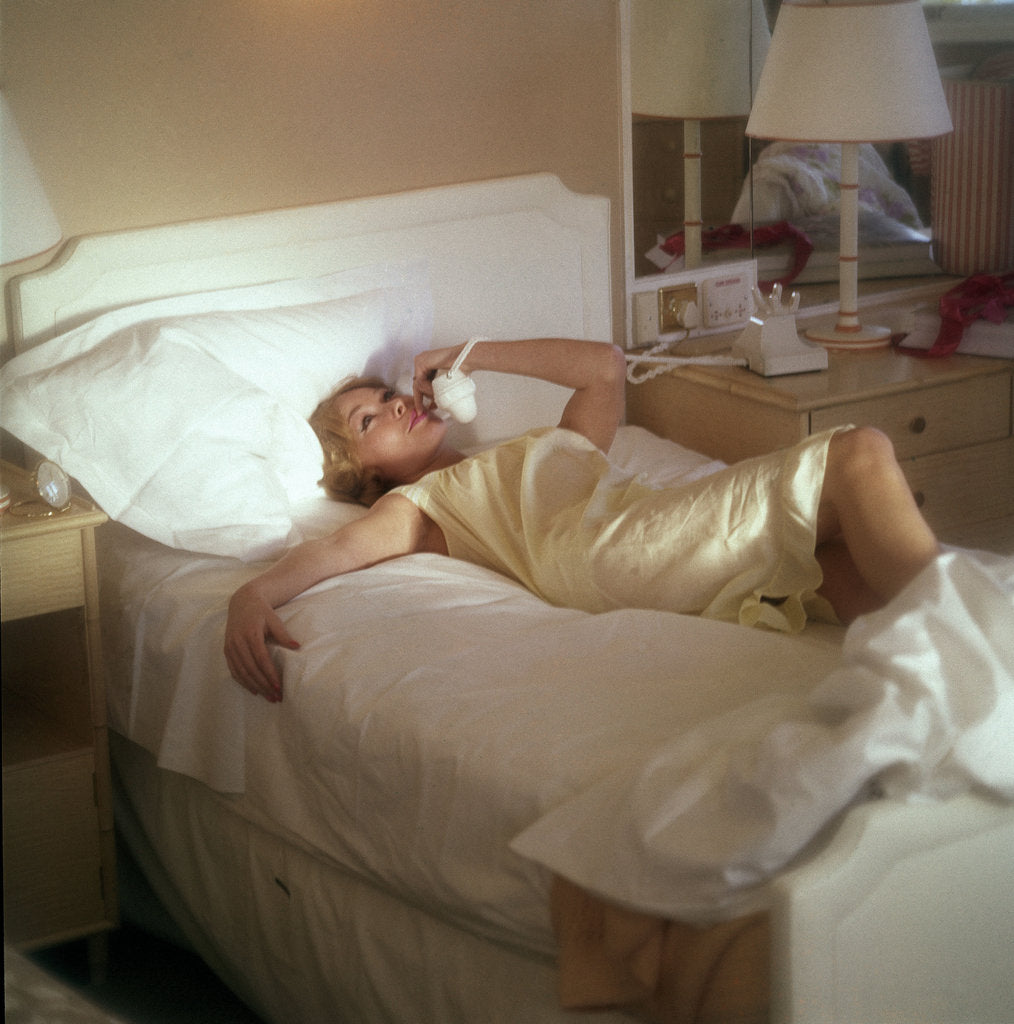 Detail of Modern convenience aboard a cruise liner: a female passenger reclines in bed whilst making a phone call; the ship and the conversation's content are unspecified by Marine Photo Service