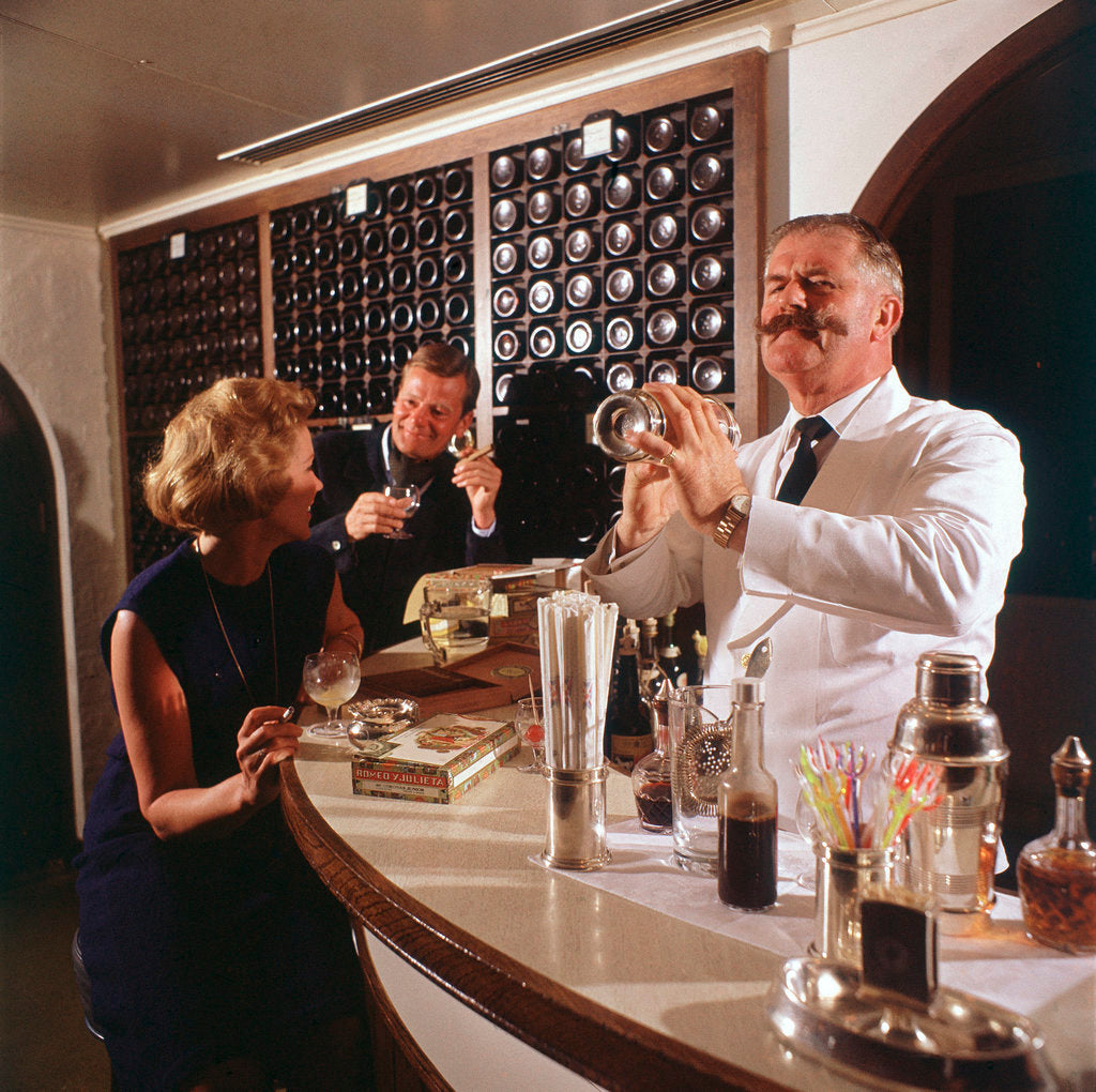 Detail of A splendidly moustachioed bartender shakes a cocktail aboard an unspecified cruise liner by Union Castle Line Collection